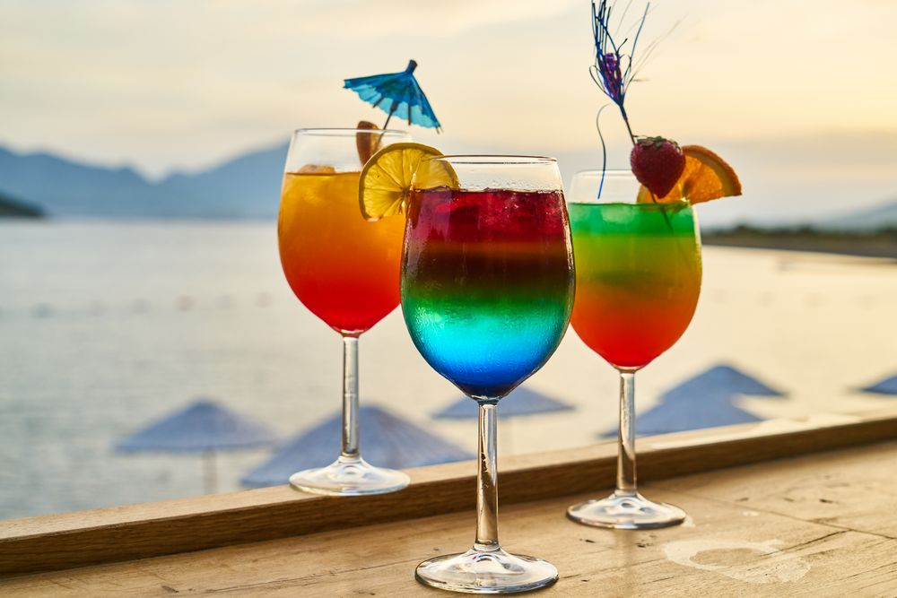 Colourful tropical cocktails on a bar counter with a coastal background