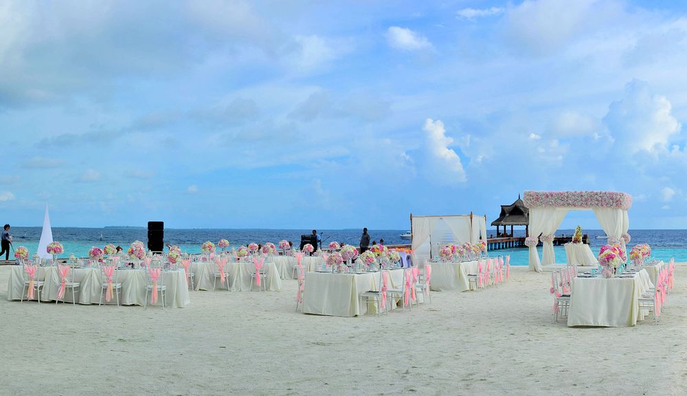 Elegantly decorated tables set up on a beach for a wedding reception at dusk